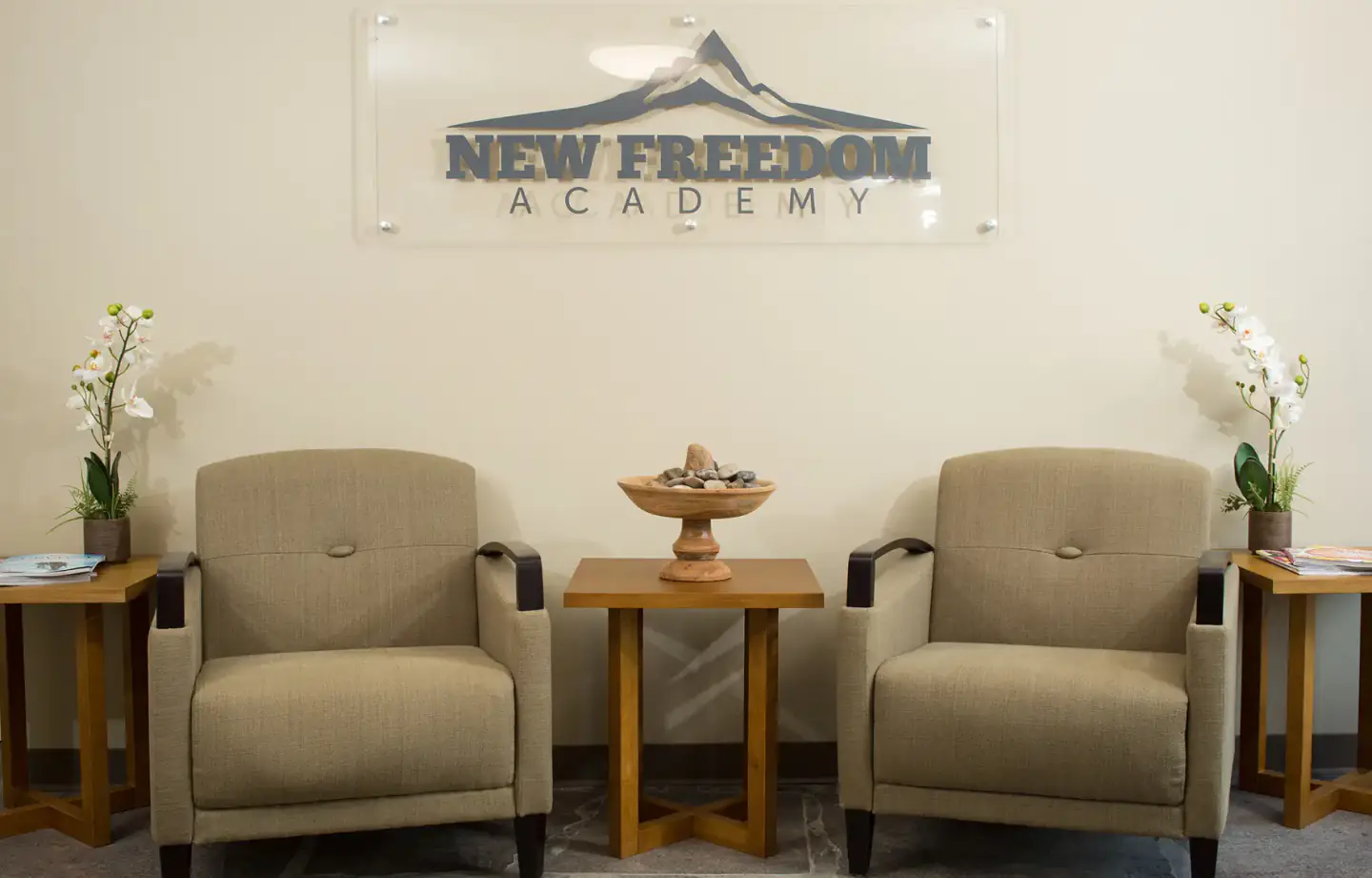 New Freedom Academy waiting area with logo sign above two chairs