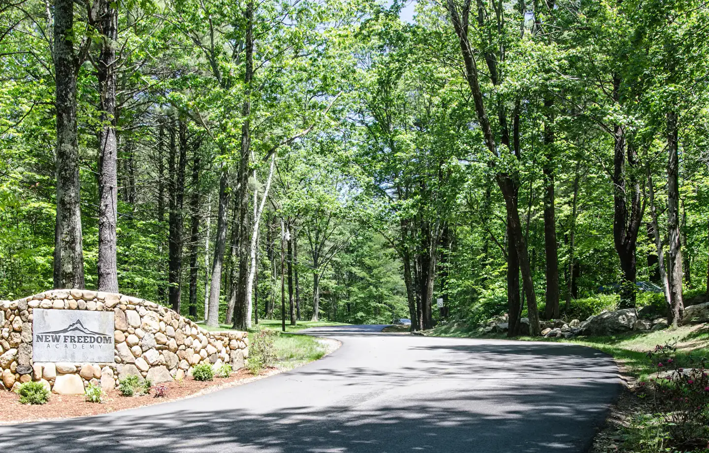 New Freedom Academy stone entrance sign and wooded driveway