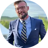 Granite Recovery clinician portrait — smiling man in suit outdoors